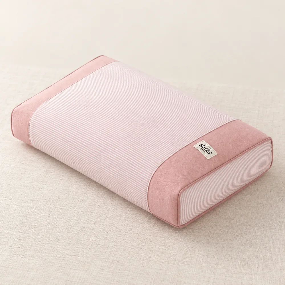 L’oreiller en sarrasin type makura Cervyne, rose à fines rayures, posé sur un tissu clair